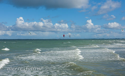 Kitesurfer an einem sonnig-frischen Tag auf der Ostsee mit Blick auf Graswarder und die Fehmarnsundbrücke