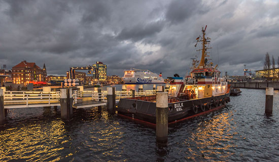Der Schlepper Bülk im Kieler Hafen unter dramatischen Wolken an einem Winterabend an der Ostsee