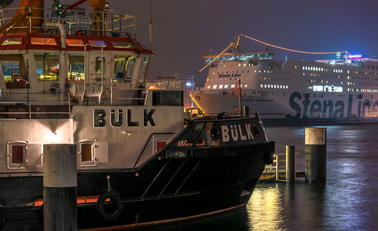 Der Schlepper Bülk und die Fähre Stena Germanica an einem diesigen Novemberabend im Hafen von Kiel