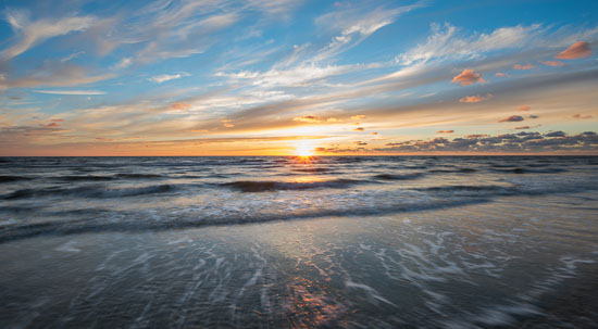 Die Sonne versinkt am Horizont der Nordsee vor dem Strand von Sankt Peter-Ording Bad