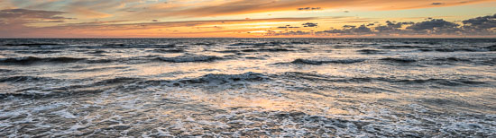 Die Wellen im Uferbereich vor Sankt Peter-Ording reflektieren das glühende Licht eines sommerlichen Sonnenuntergangs am Horizont der Nordsee