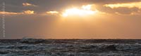  Die Abendsonne bricht vor  Sankt Peter-Ording durch die Wolken über den Wellen der aufgewühlten Nordsee