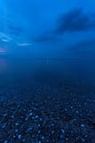  Blick vom Strand von Heiligenhafen nach Flügger Sand –  DETAIL: Dieses Foto zur späten, blauen Abendstunde, zeigt den Strand von Heiligenhafen – mit, im Flachwasser liegenden Kieseln und Muscheln – sowie Blickrichtung auf den Flügger Leuchtturm.