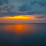  Sonnenuntergang über der Ostsee vor Heiligenhafen –  DETAIL: Über dem Horizont liegt eine dicke Wolkenbank, das Licht des Sonnenuntergangs ist kräftig rot-orange und die Wolken heben sich bläulich drohend ab. Die Ostsee reflektiert das warme Abendlicht.