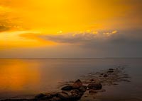  Steinbuhne im Sonnenlicht vor Graswarder am Fehmarnsund –  DETAIL: Die tief stehende Abendsonne taucht den Strand von Heilgenhafen in ein magisches Licht. Der Hintergrund des Fotos zeigt die Süd-West-Spitze von Fehmarn mit dem Flügger Leuchtturm.