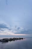  Steinbuhne im Licht der untergegangenen Sonne am Strand von Heiligenhafen –  DETAIL: Dieses hochformatige Meeresfoto zeigt eine Buhne aus großen Steinen, vor dem abendlichen Horizont am Strand von Heiligenhafen. Am Himmel ziehen einzelne Wolken ihre Bahnen.