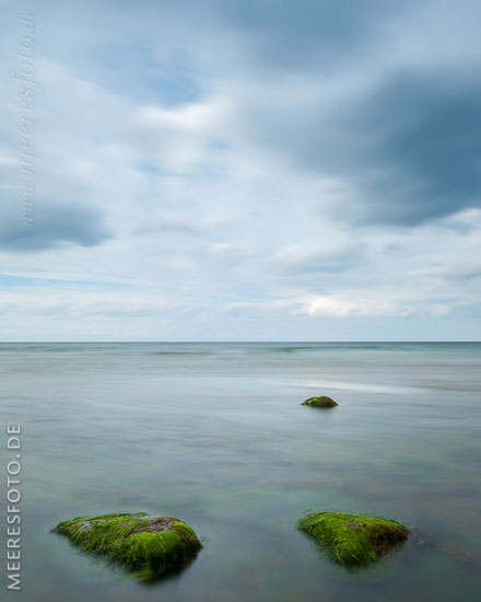  »Bewachsene Steine vor Hohenfelde« DETAIL: Im Uferbereich am Strand von Hohenfelde liegen diese mit Algen bewachsenen großen Steine. Das hochformatige Foto zeigt eine reduzierte Farbigkeit und eine harmonische Lichtstimmung.