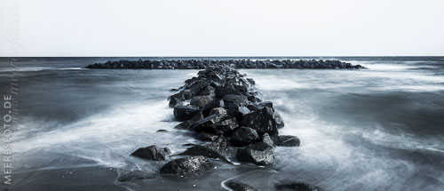  Steinbuhne in den Wellen am Strand von Schönberg – monochrom