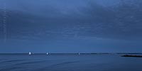  In die Kieler Förde einlaufende Segelschiffe zur blauen Stunde an einem Sommerabend vor Strande –  DETAIL: Das Foto zeigt Segelboote auf der Kieler Förde, an einem warmen Abend im Hochsommer. Am Horizont erkennt man das beleuchtete Seebad Laboe.