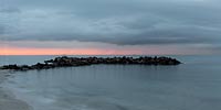  Eine Steinbuhne bei Heidkate im späten Abendlicht eines Tages im Frühjahr –  DETAIL: Am Horizont sind Frachtschiffe und der Leuchtturm „Kiel“.