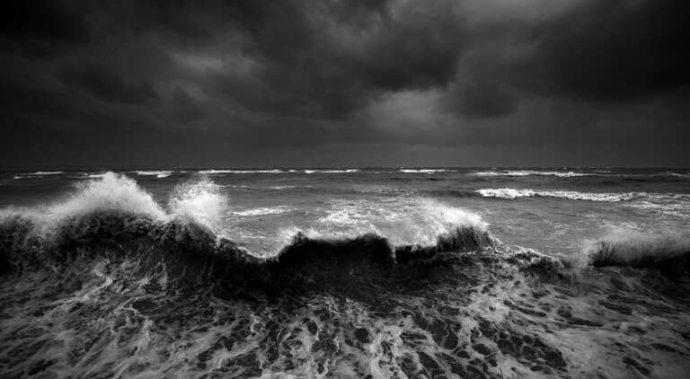 Brandungswelle mit Gischtsaum unter einem bedrohlichen Himmel