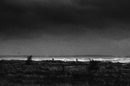 Zwei Personen machen Handyfotos von der Sturmflut vor den Dünen von Laboe.