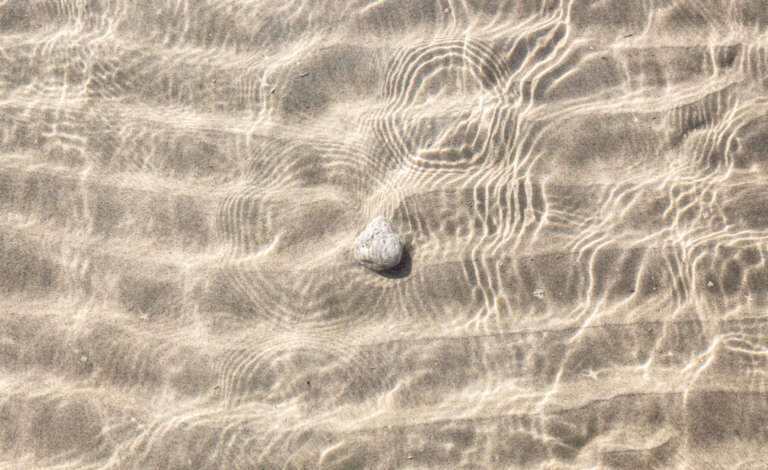 Stein und Sandwellen im Flachwasser